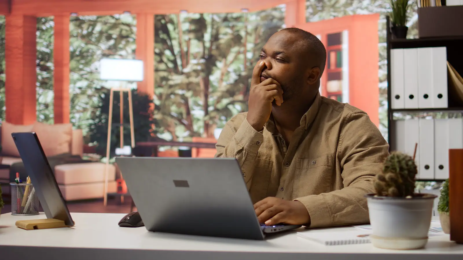 A vendor at his desk, hand over his mouth, thinking with everything still in his head