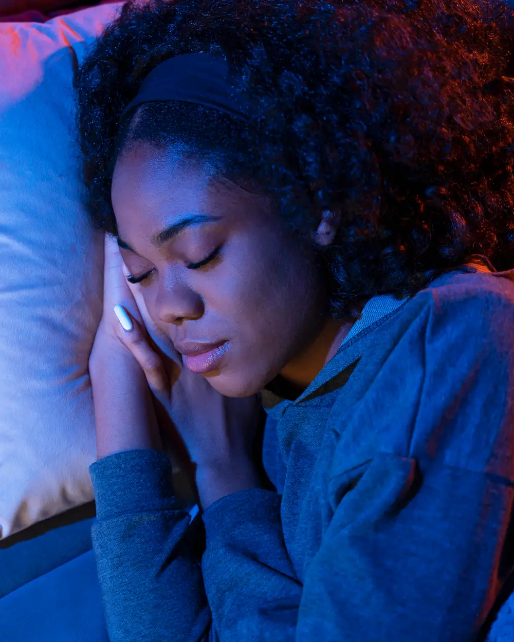 Chioma asleep on a pillow in dim blue night light, her hand under her cheek
