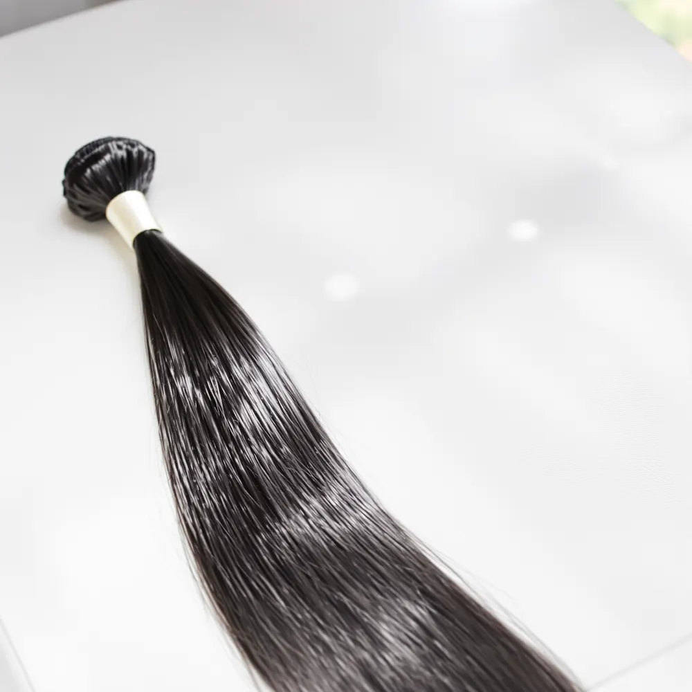 A bundle of glossy bone straight hair on a white surface