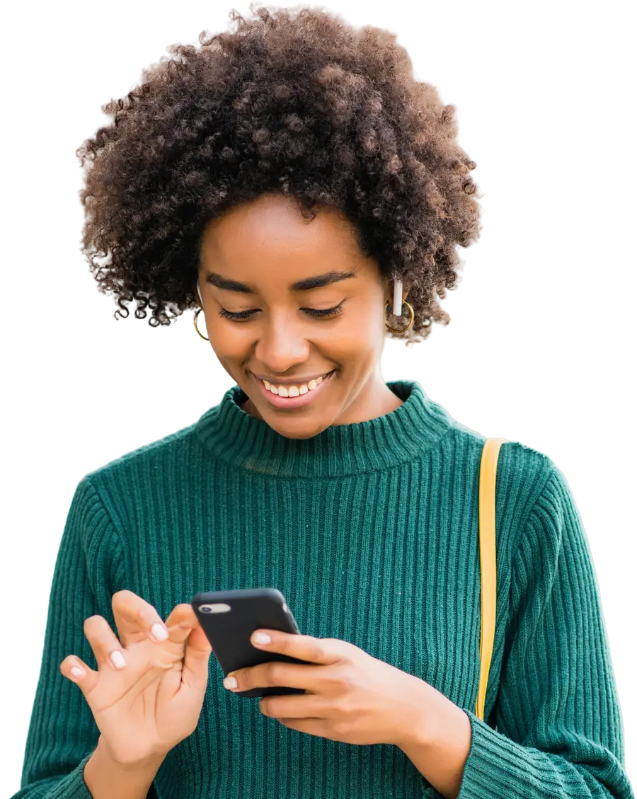 A young vendor smiling at her phone, out in the daylight